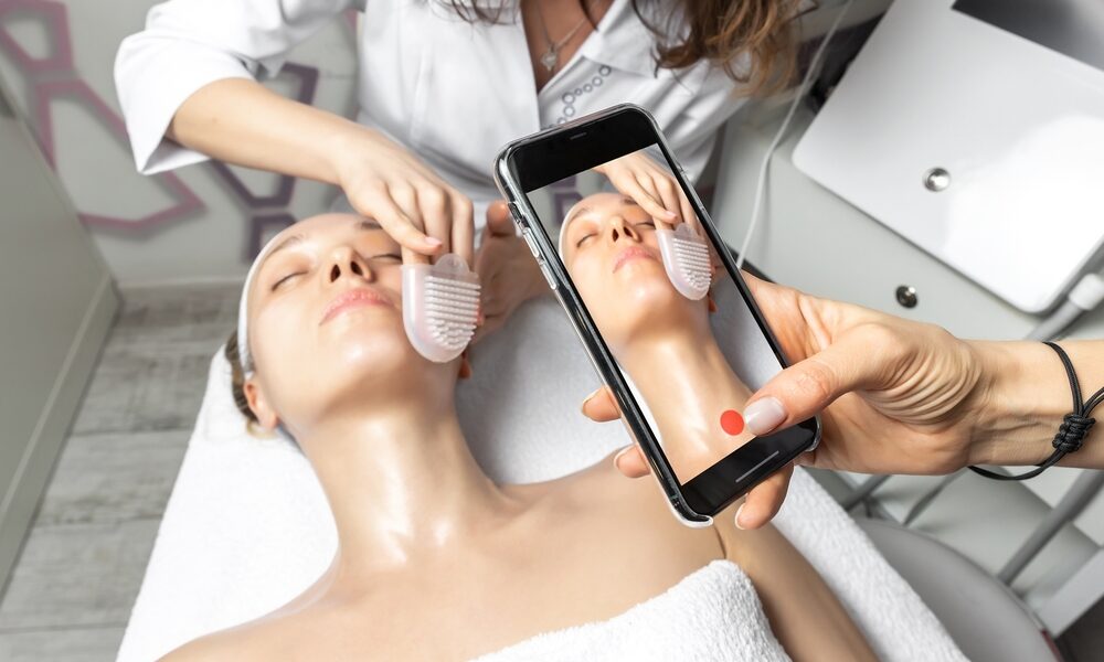 Mulher usando celular para gravar rosto de mulher sendo tratado