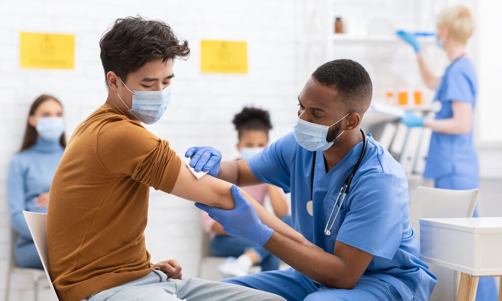 Enfermeiro utiliza pano para limpar o braço após aplicar vacina