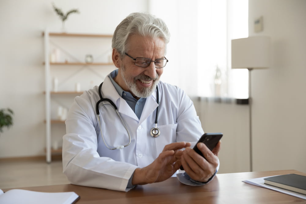 médico olhando celular e buscando ideias de posts para sua rede social